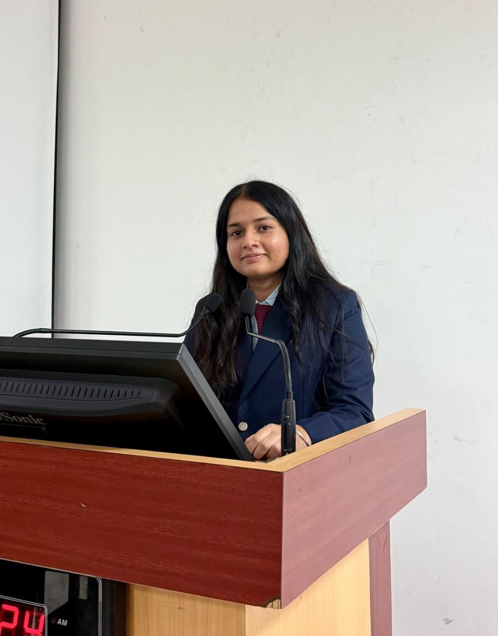 Portrait of Ritika Gautam speaking at a podium